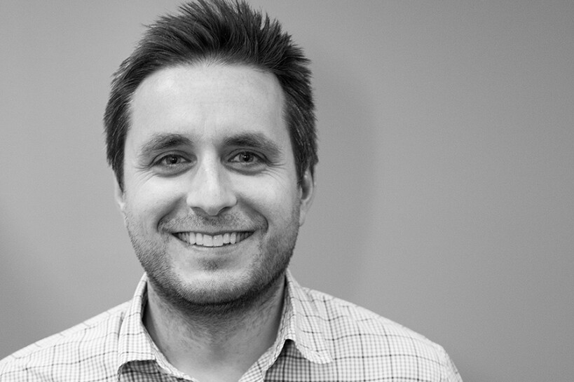 Portrait of children's author, Mike Petrik. He's wearing a checkered button-down shirt in front of a neutral background.