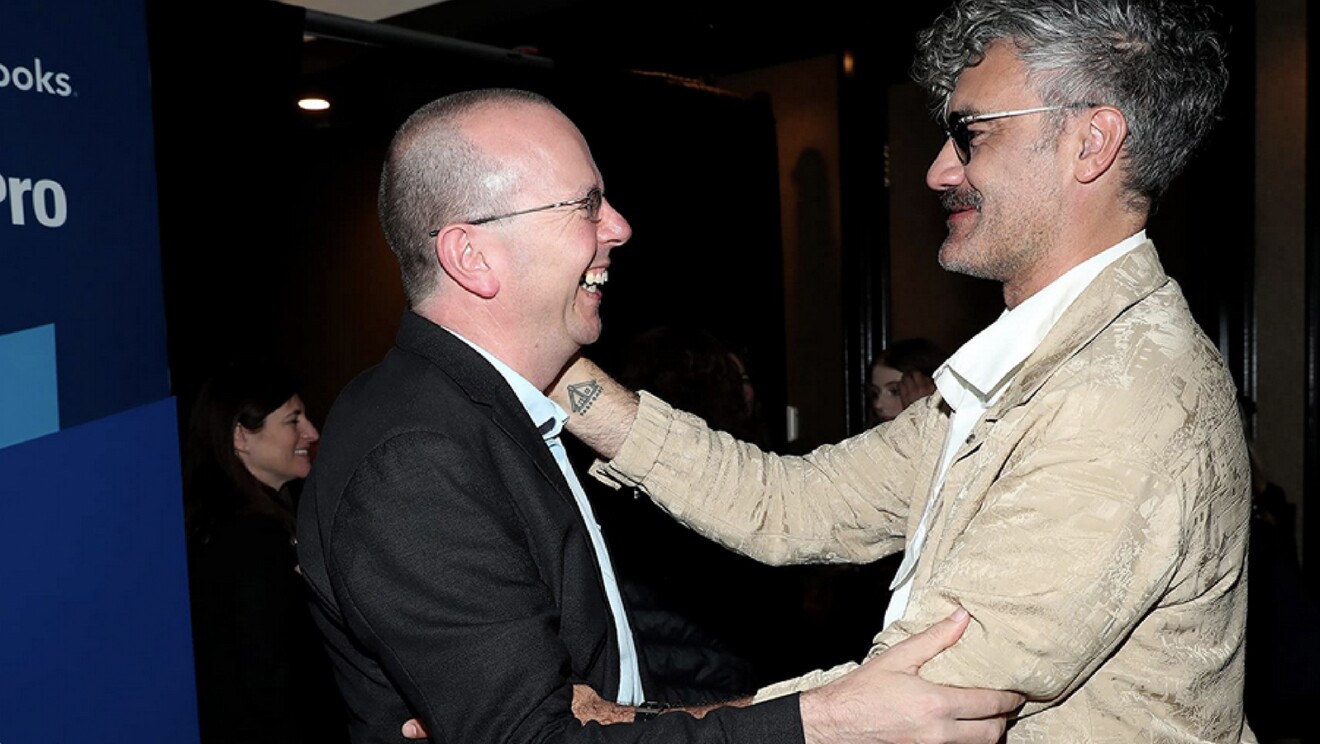 A photo of Col Needham, founder and CEO of IMBD, Embracing Taika Waititi.