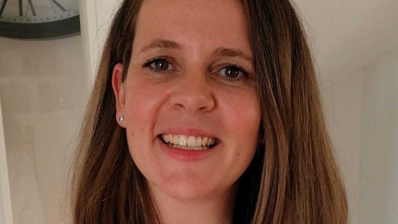 Eine Frau mit kurzen blonden Haaren lacht in der Kamera.