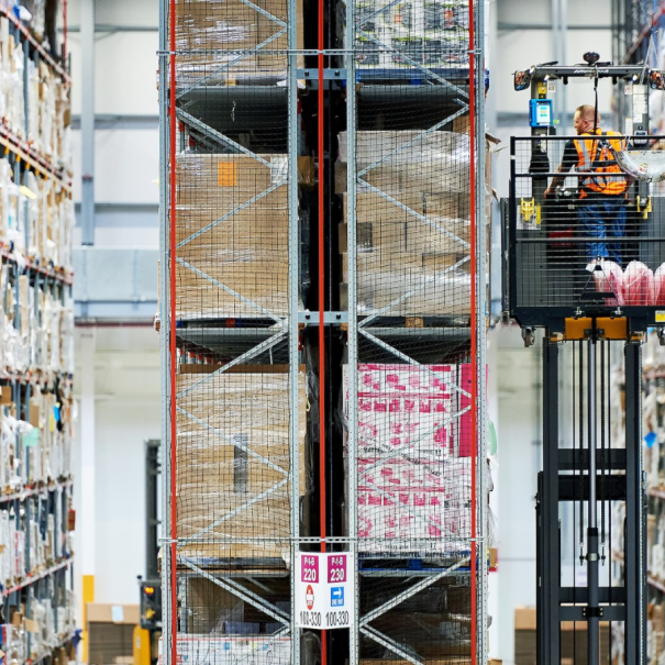 Massive shelves in Amazon fulfilment centre with man on lift retrieving items
