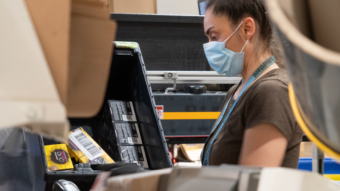 Dipendente Amazon in un centro di distribuzione. La donna indossa una mascherina.