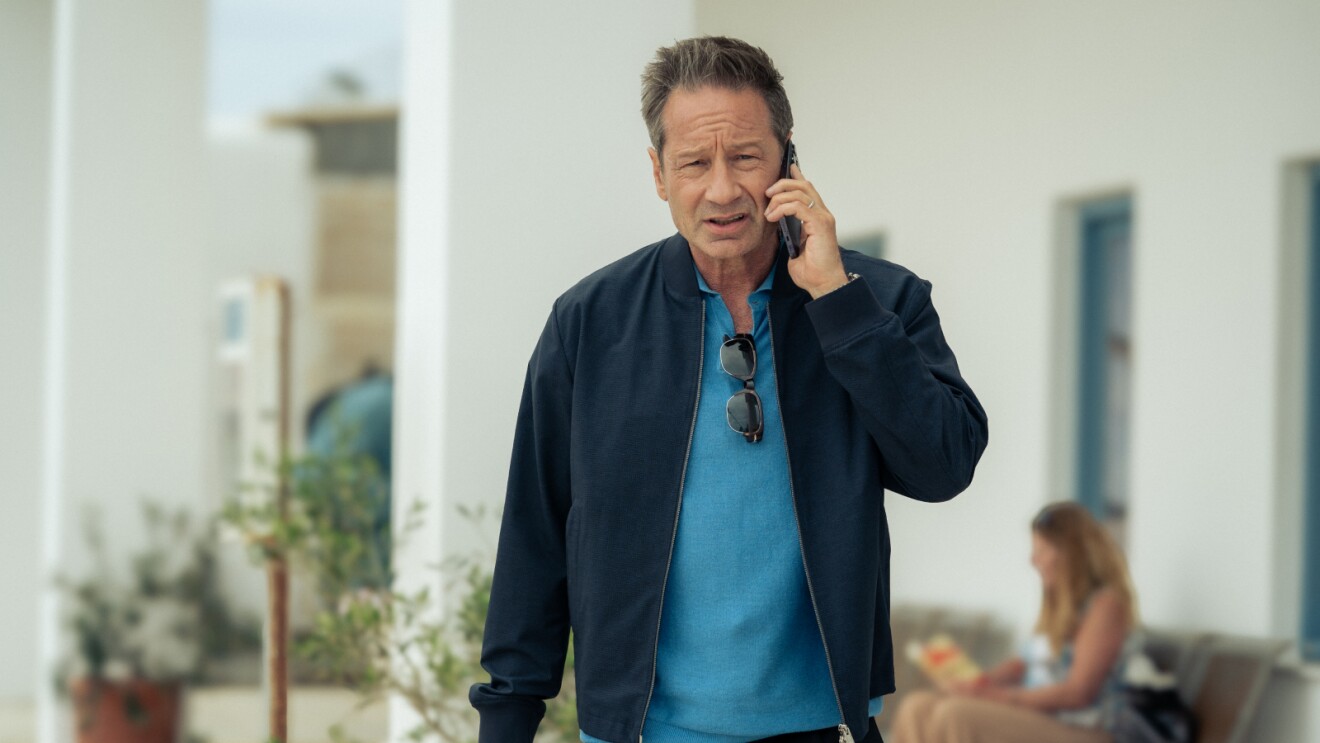 Middle-aged man in blue shirt and jacket speaking on phone outdoors
