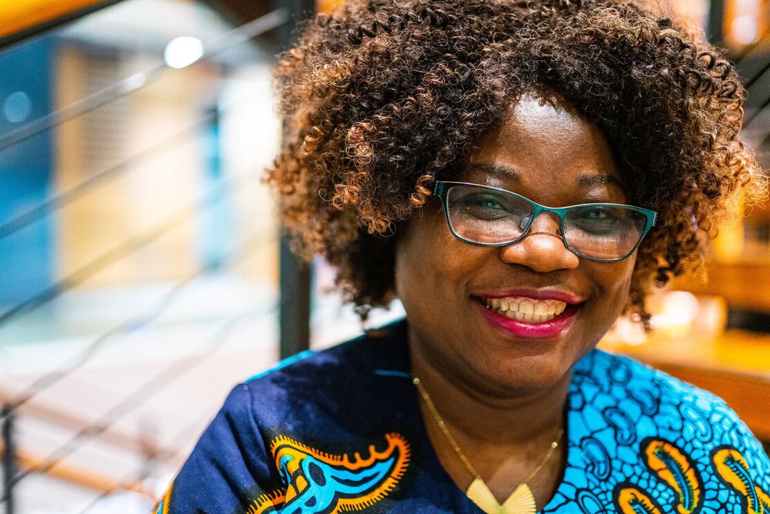 A headshot image of a woman smiling for a photo in front of steps in Amazon's office.