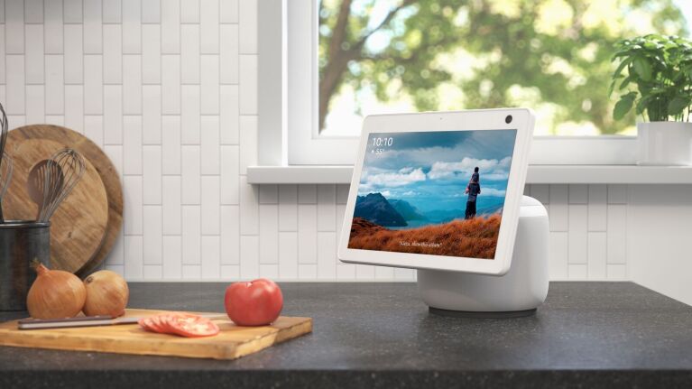 The Amazon Echo Show 10 on a kitchen counter with the time, weather and a photo displayed on the screen.