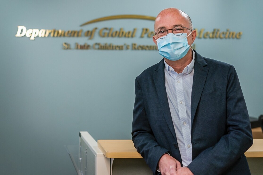 A photo of Dr. Galindo, childhood cancer researcher and physician, wearing a surgical mask and smiling in front of a desk at the St. Jude Children's Research Hospital.