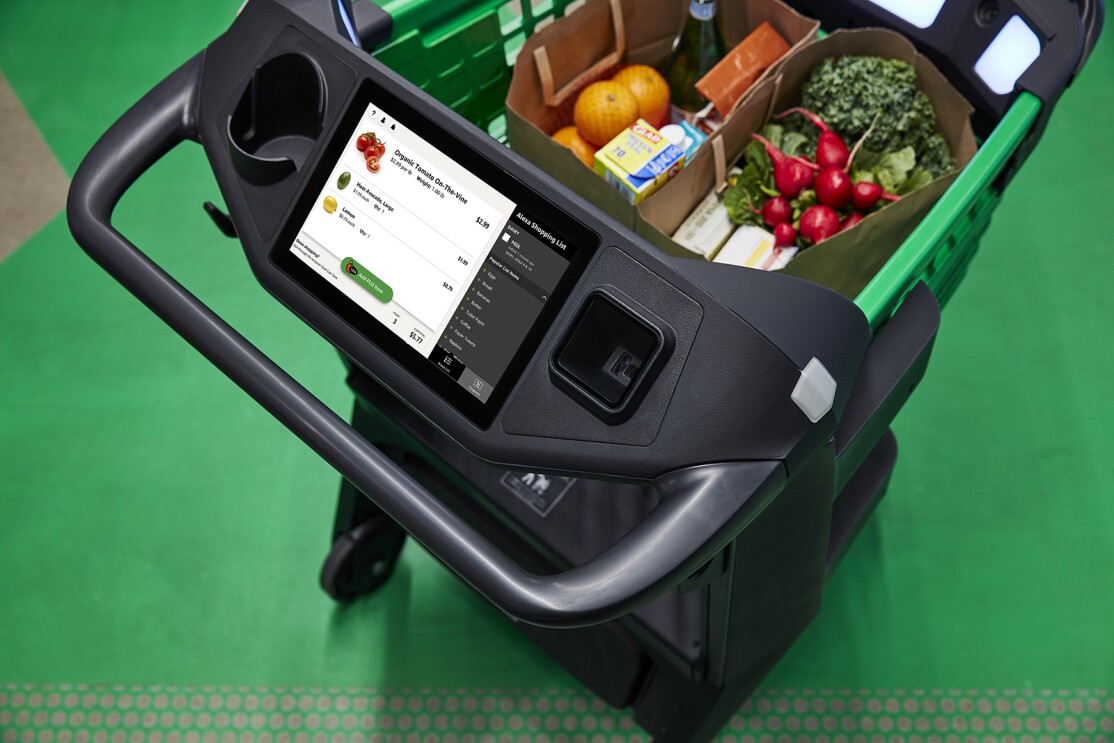An image of an Amazon Dash cart. It is a grocery cart with a screen on it. On the screen you see the items in the cart, their individual prices, and the running total.