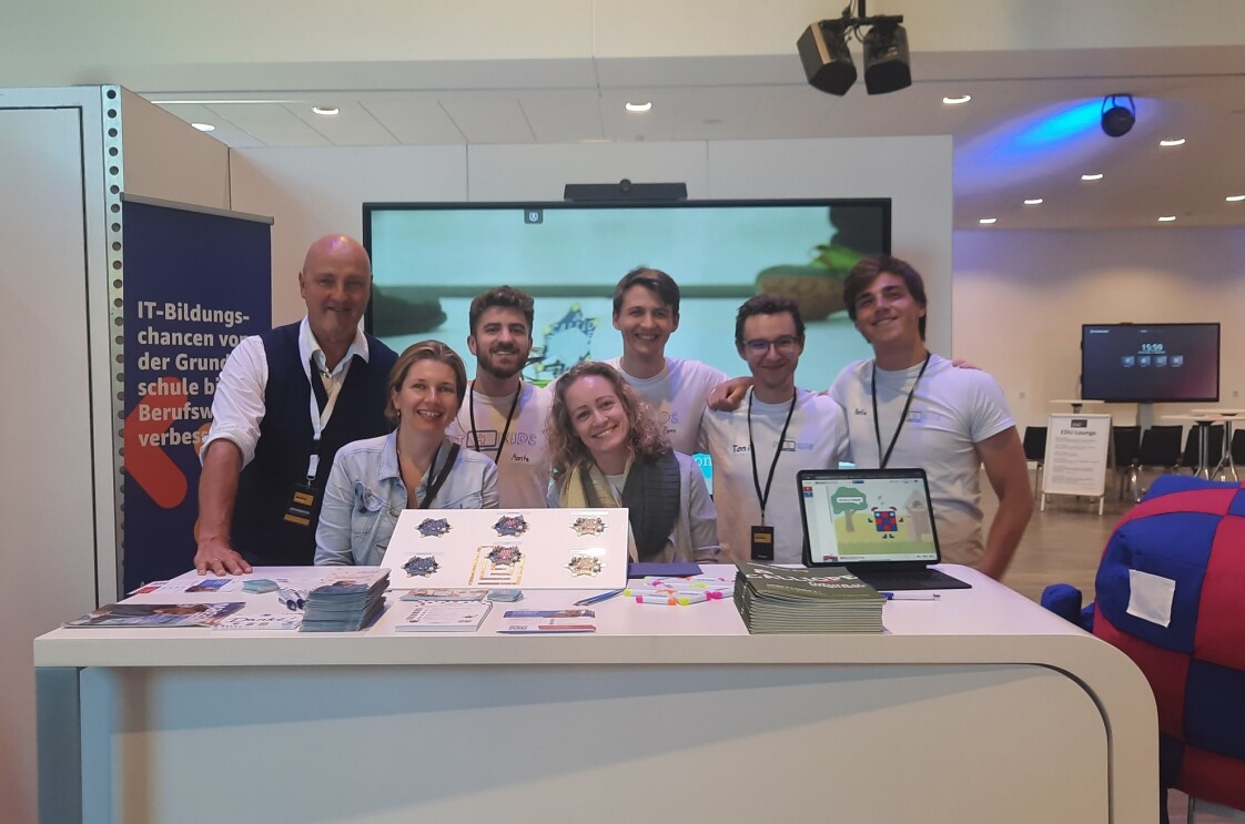 Gruppenbild von Amazon Future Engineers vor einem großen Bildschirm auf einer Messe.