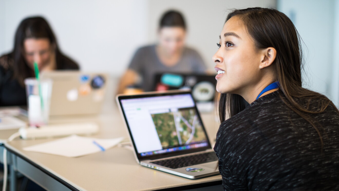 A woman works on a laptop computer in a conference room 