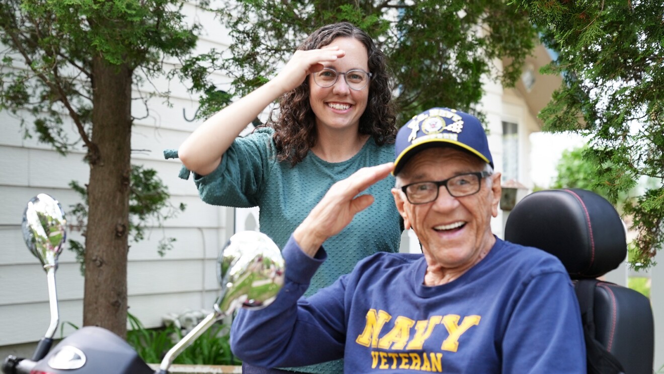 Patriotic Kenny and friend Amanda smile while saluting.