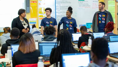 A teachers stands in front of her class alongside three Amazon Future Engineer volunteers.