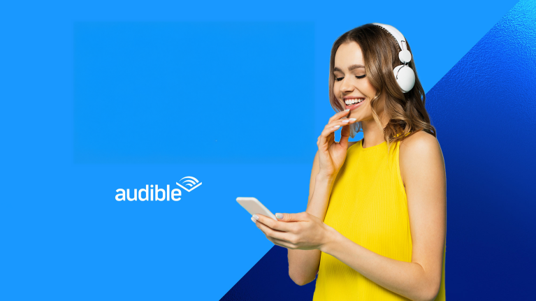 Frau in gelbem Oberteil lächelt, während sie die Audible-App mit Kopfhörern nutzt.