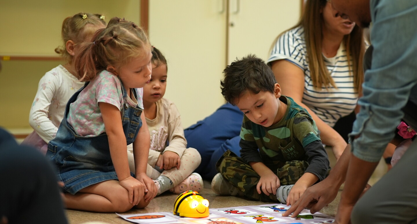 Alumnos de primaria con un robot de lego en el suelo. 