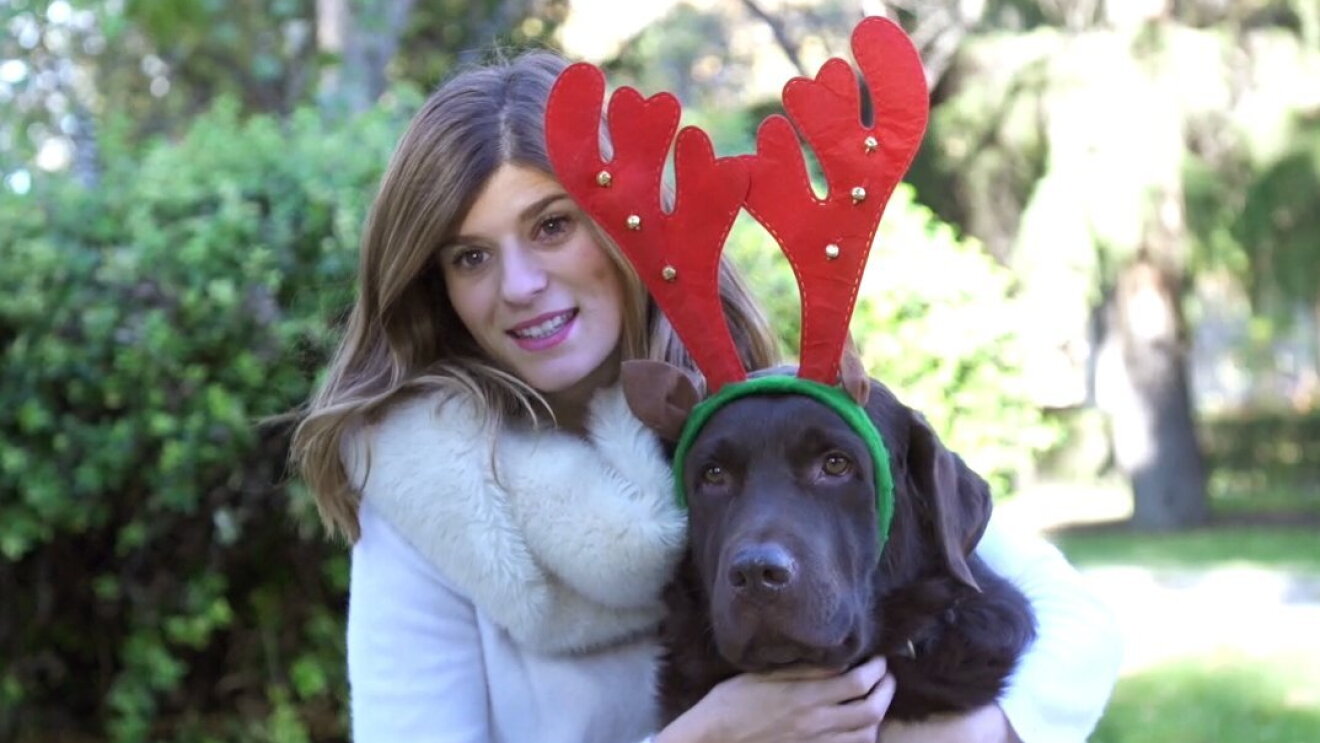 Marina Oliveira es portuguesa y trabaja en las oficinas corporativas de Amazon en Madrid. En la foto aparece con su perro, un labrador de color negro, que luce un diadema de reno. Ella es rubia y está sonriente. Están los dos en un parque. 
