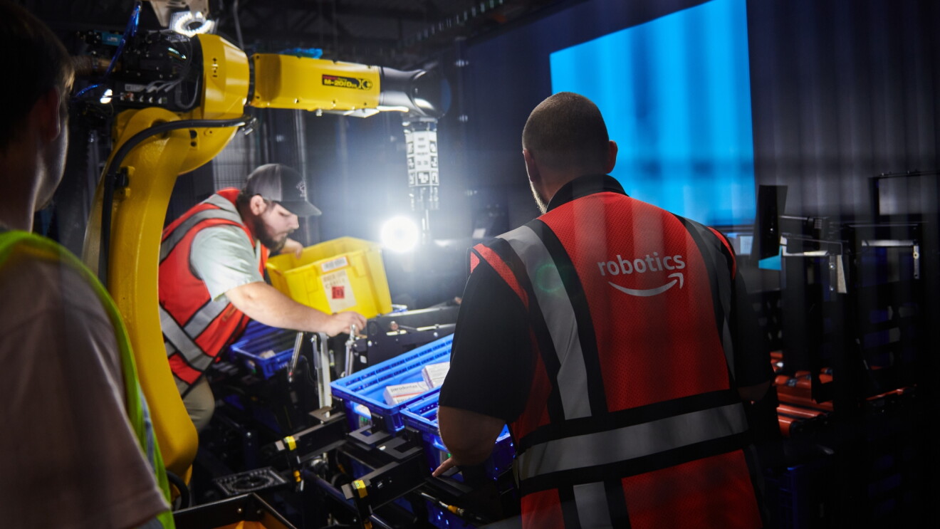 Amazon employees interacting with industrial robot and conveyor
