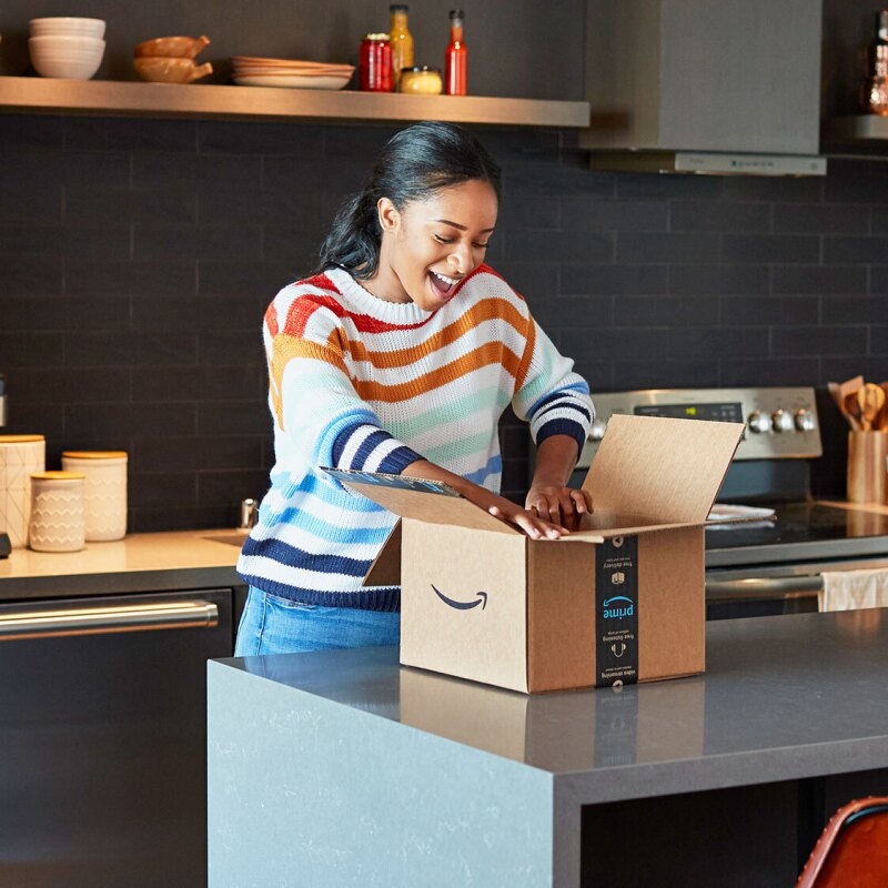 一位女士在厨房里打开亚马逊的包裹时非常兴奋。