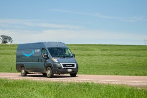Amazon Prime delivery van on rural road with farmhouse in background