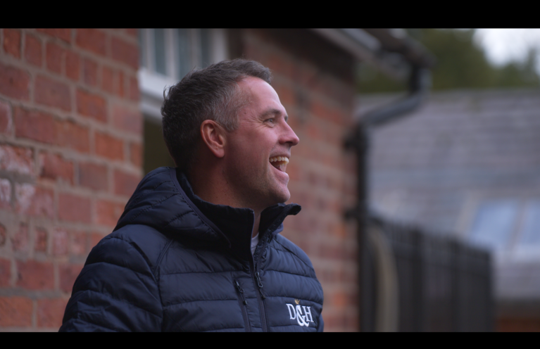 Michael Owen smiles while facing away from the camera 
