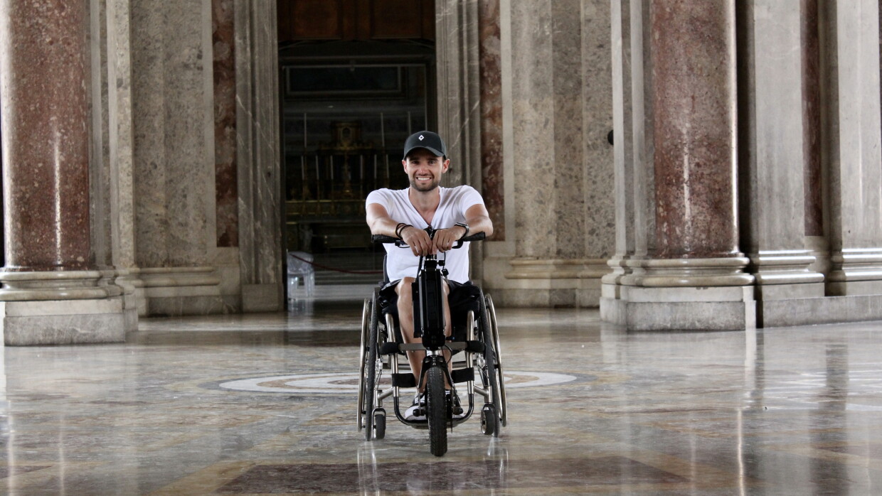l'immagine mostra un giovane dipendente amazon in carrozzina nel suo tempo libero, al centro di una hall di un palazzo storico