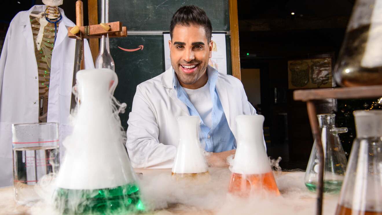 Dr. Ranj Magic Breakfast in front of a table filled with test tubes and science experiments.