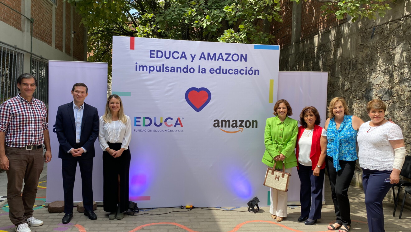 Foto de siete personas posando delante de un cartel con el logo de Educa y Amazon y el texto Educa y Amazon, impulsando la eudcación. 