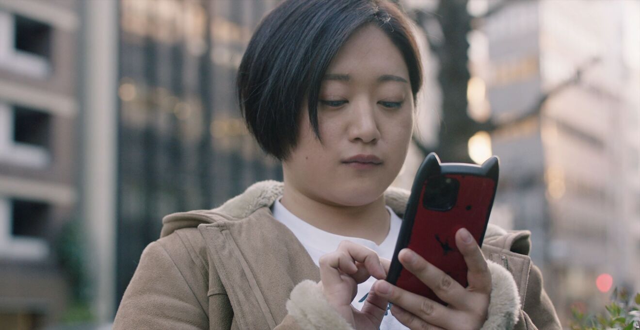 屋外で短い髪の女性が携帯を見ている