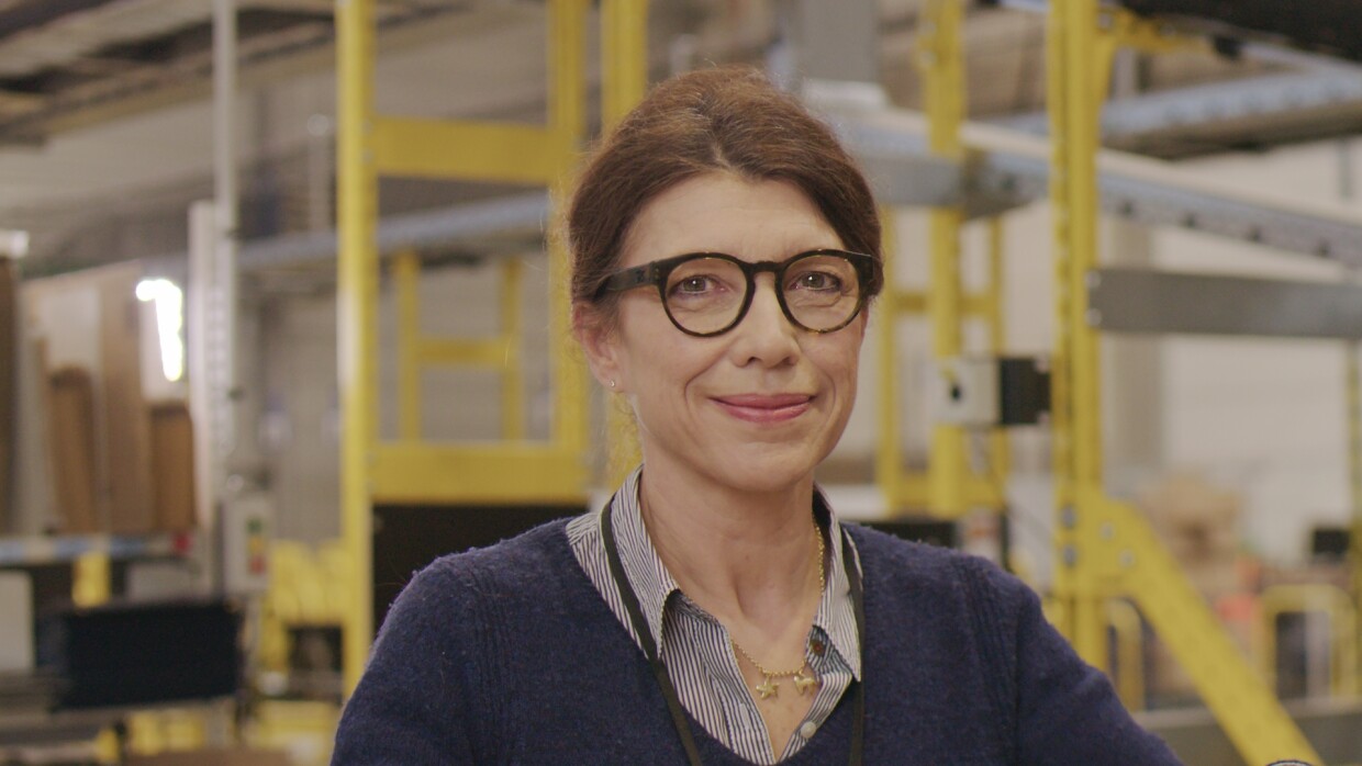 Une femme ferme un carton Amazon dans le centre de distribution de Chalon sur Saône. Le décor de fond est le centre de distribution
