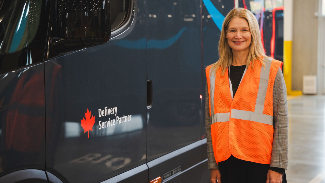 Image of a woman posing in front of an Amazon x Rivian delivery van