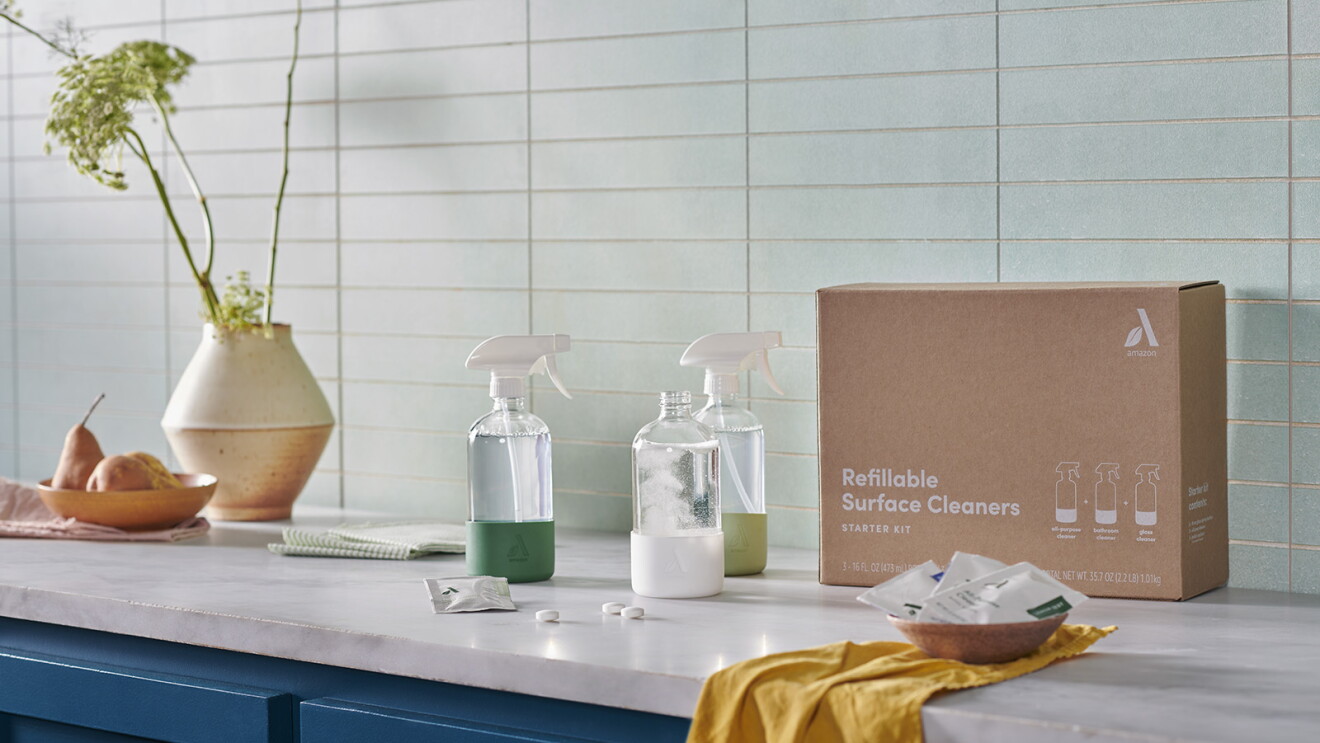 An image of cleaning products and a cleaning cloth sitting on a kitchen counter. There is a brown box beside the products that they were delivered in.