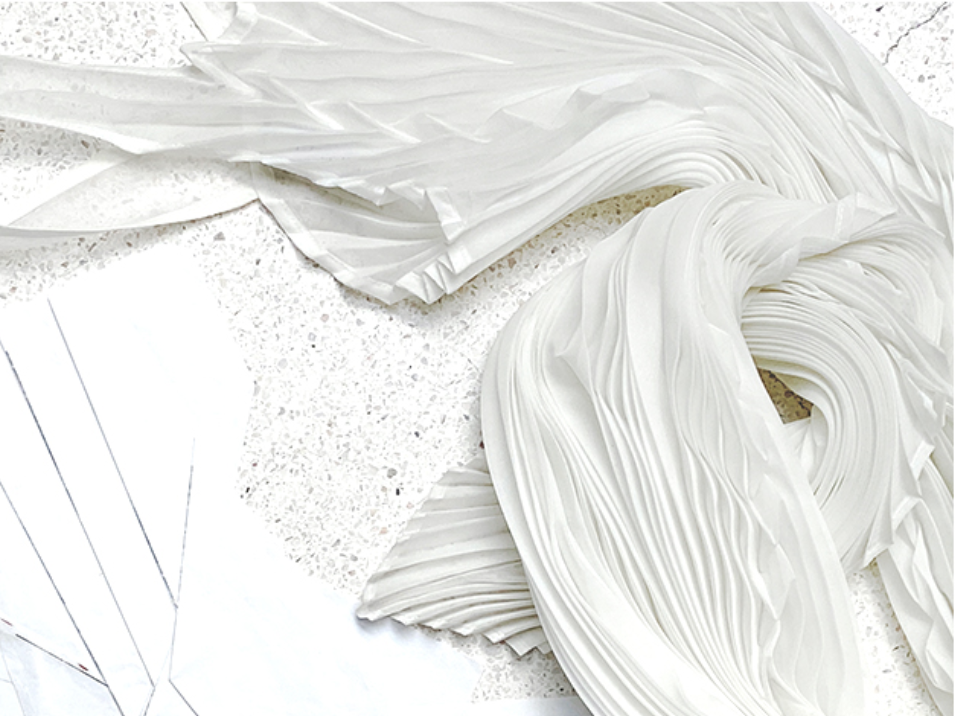 Pleated cloth strewn across a table with drawings