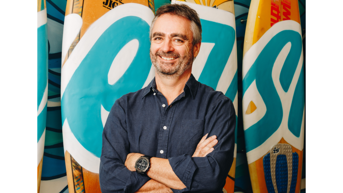 Robert Koen, managing director of Sub-Saharan Africa at Amazon stands in front of surfboards and smiles.