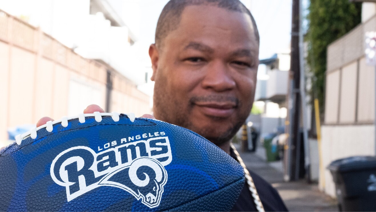 TV personality Xzibit holding a blue Los Angeles Rams football. 