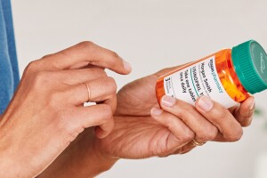 image of pair of hands one is holding a bottle of lisinopril prescribed through amazon pharmacy