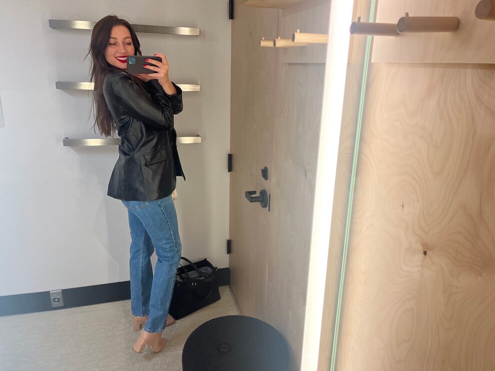 A woman takes a selfie in a new outfit inside the Amazon Style fitting room.