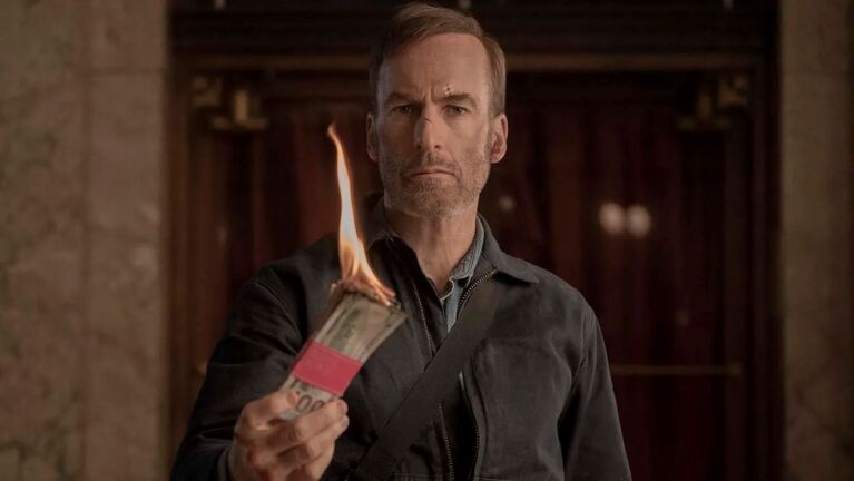 Bob Odenkirk holding up banknotes on fire
