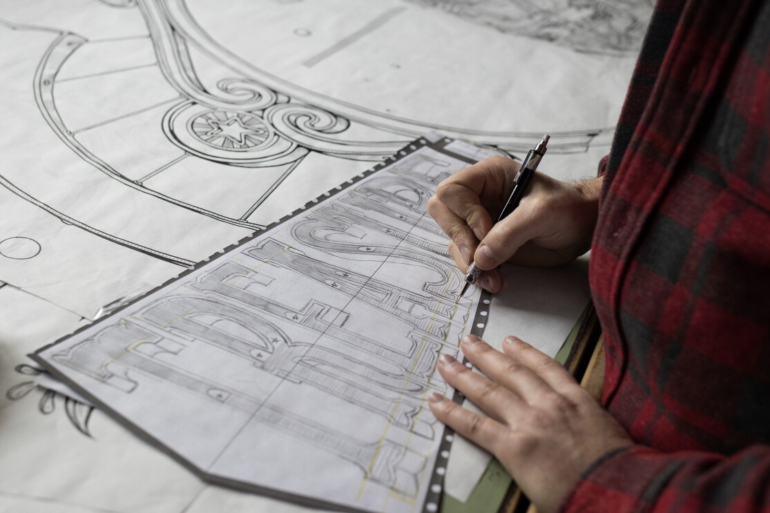 Kyler Martz in his Seattle studio. He is drawing the word TREASURE onto a large piece of paper.