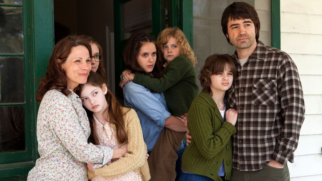 The Conjuring movie: Family of seven posing on porch of white house with green trim