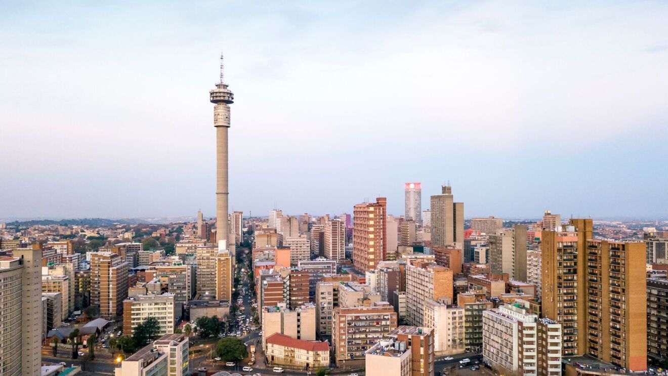 Johannesburg city skyline at dusk with the iconic Hillbrow Tower rising above residential and commercial buildings