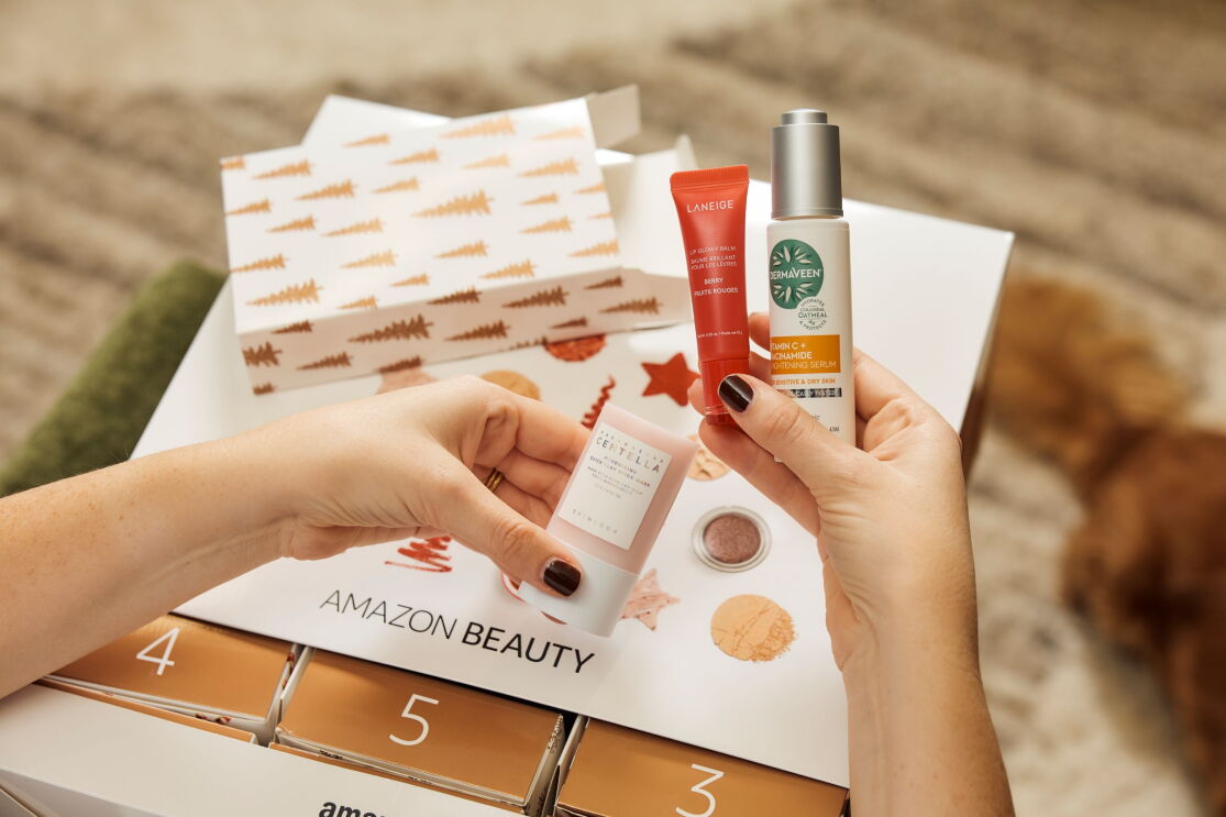 Woman on a couch holding up three products from the 2025 Amazon Beauty Advent Calendar.