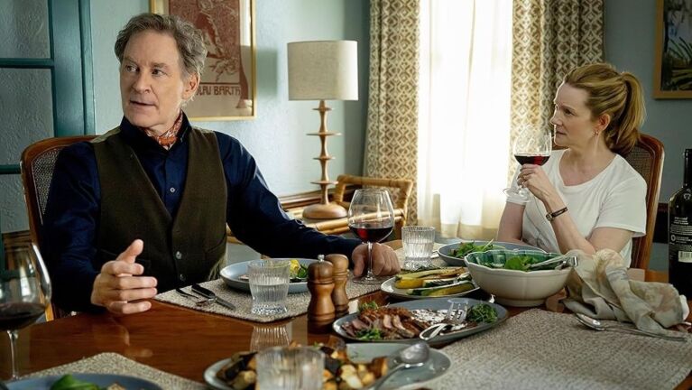 Man and woman share a meal at a table in a home, each with a glass of wine