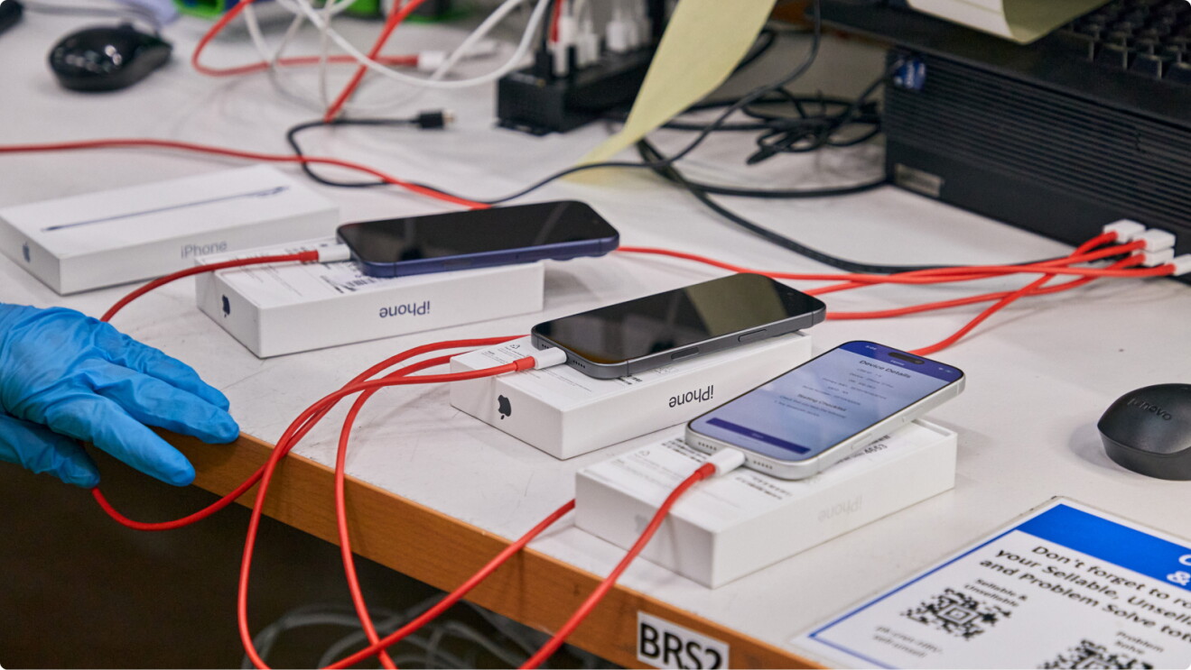 Multiple iPhones connected to charging cables on a desk, ready for data-wiping