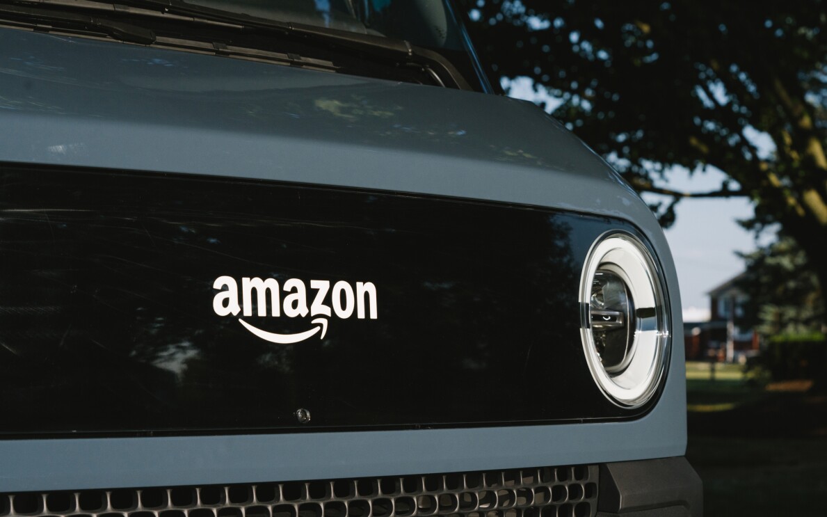 Detail of the front of an electric delivery vehicle, showing the Amazon logo a headlight.