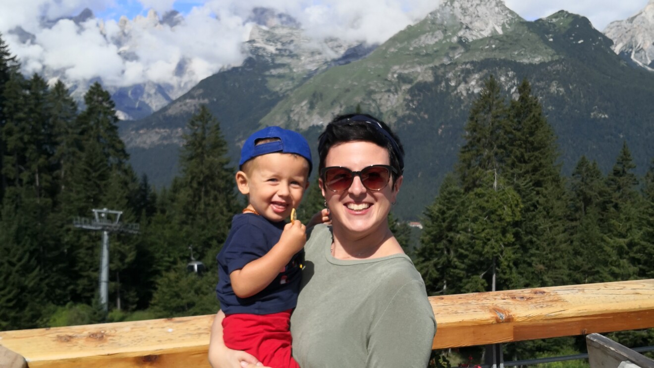 Una volontaria Amazon posa con in braccio suo figlio. Si trovano in un ambiente montano.