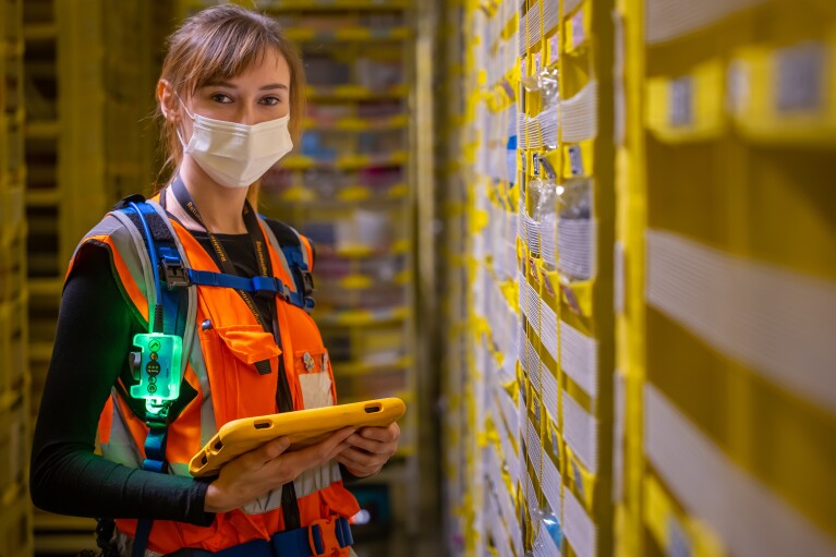 Eine junge Frau mit Sicherheitsweste in einem Amazon Logistikzentrum.