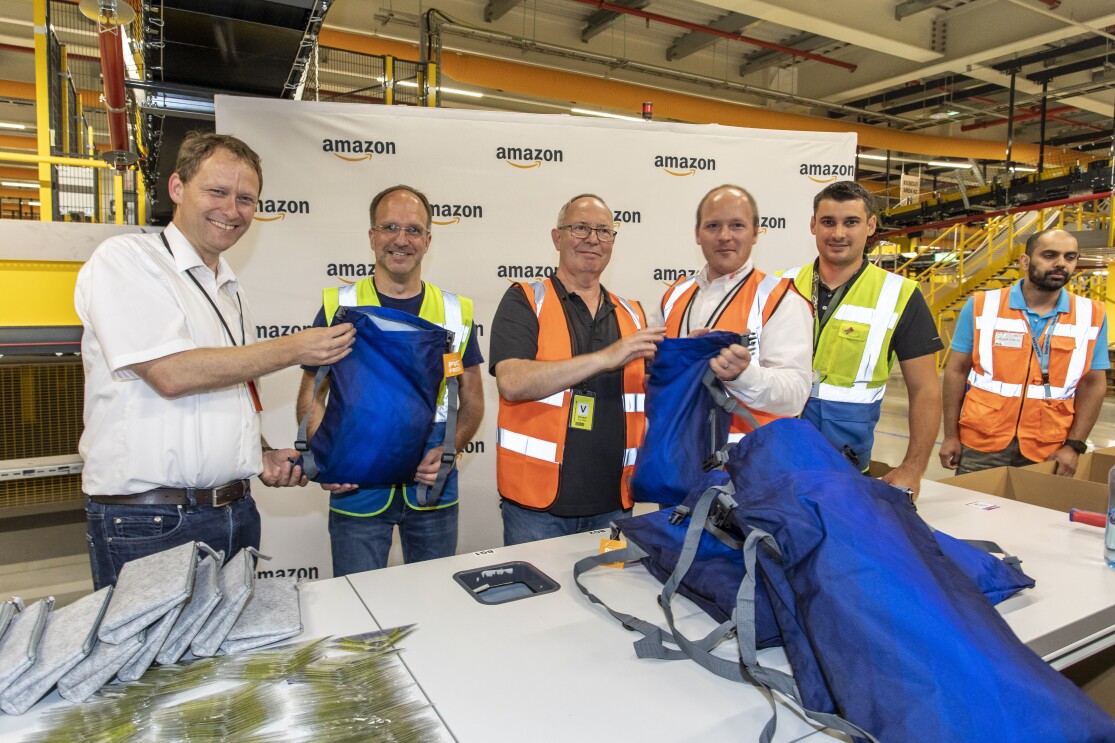 Verschiedene Personen in Sicherheitswesten packen an einem Packtisch.