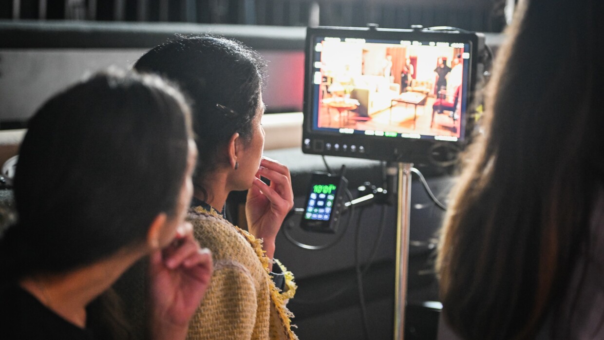 Film crew watching monitor displaying living room set during production