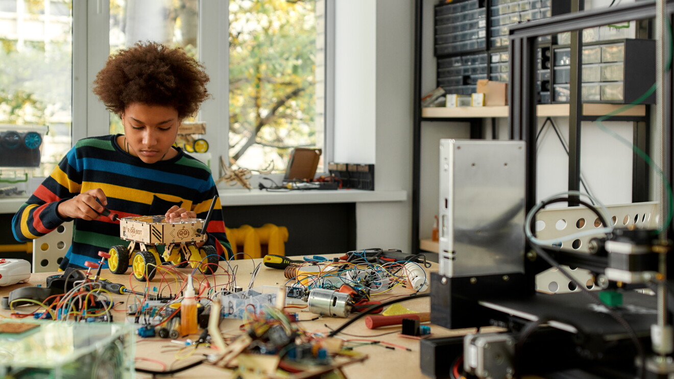 A photo of a student working on a robot within an engineering classroom.