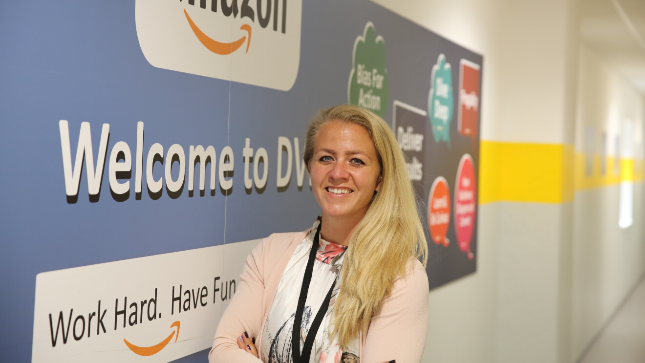 Eine blonde Frau vor einem Amazon Plakat