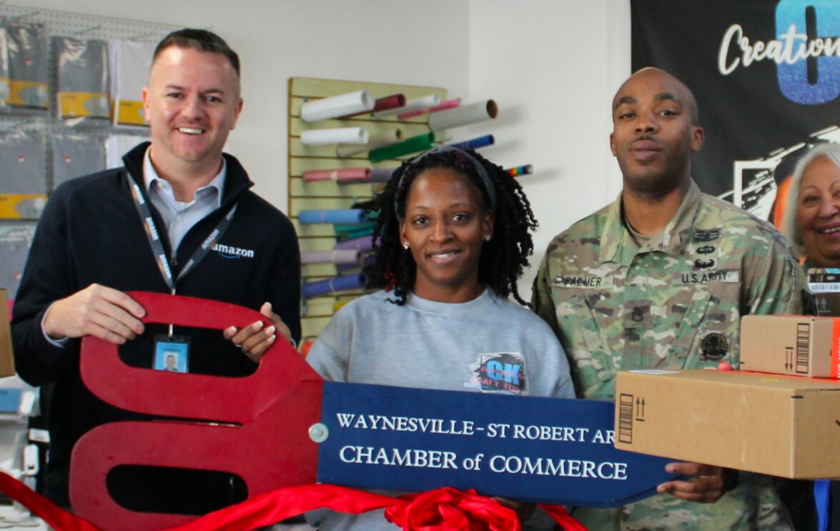 LaKeisha Palmer stands between a man wearing a sweater with an Amazon logo and a man wearing a U.S. army uniform.