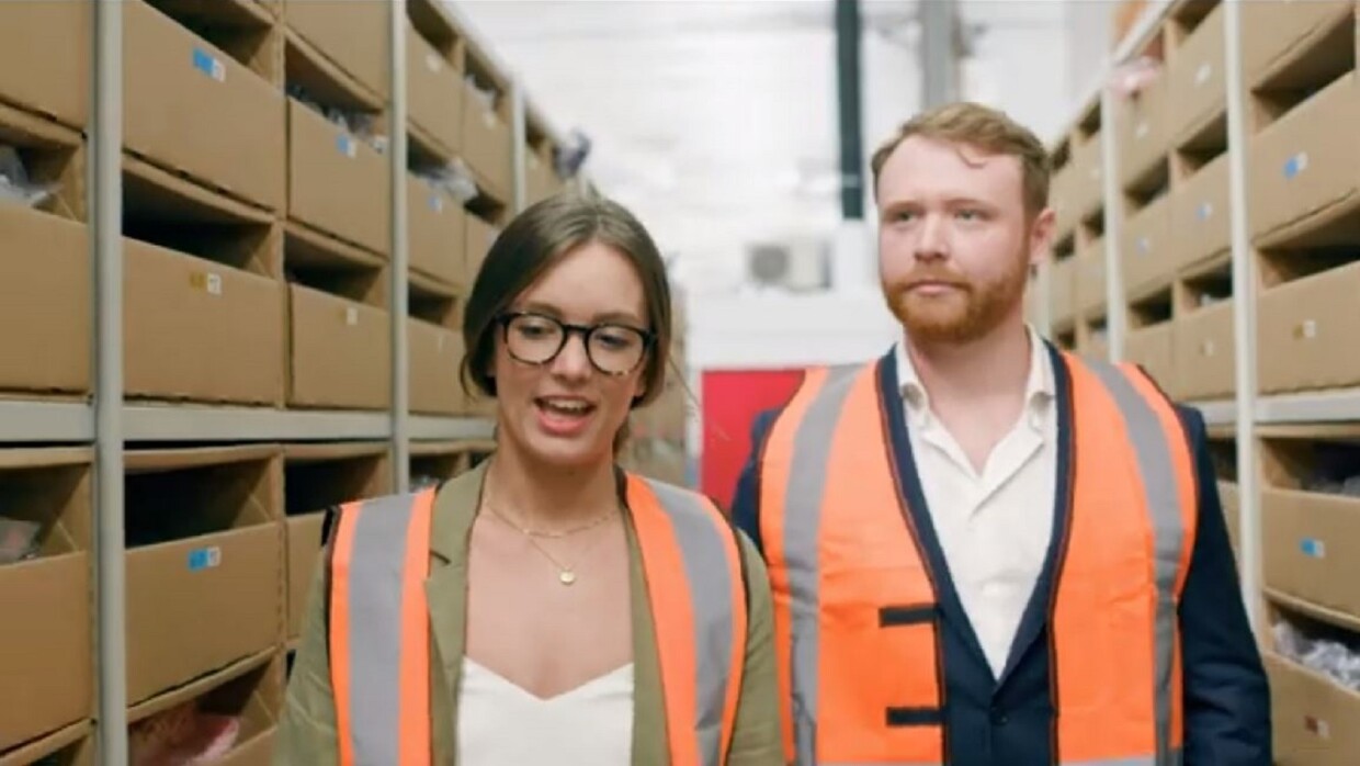 Woman and a man in high-vis walking through a warehouse eisle