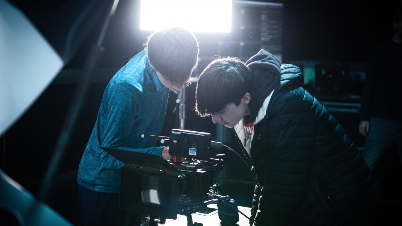 Two people intently examining professional camera equipment on set

